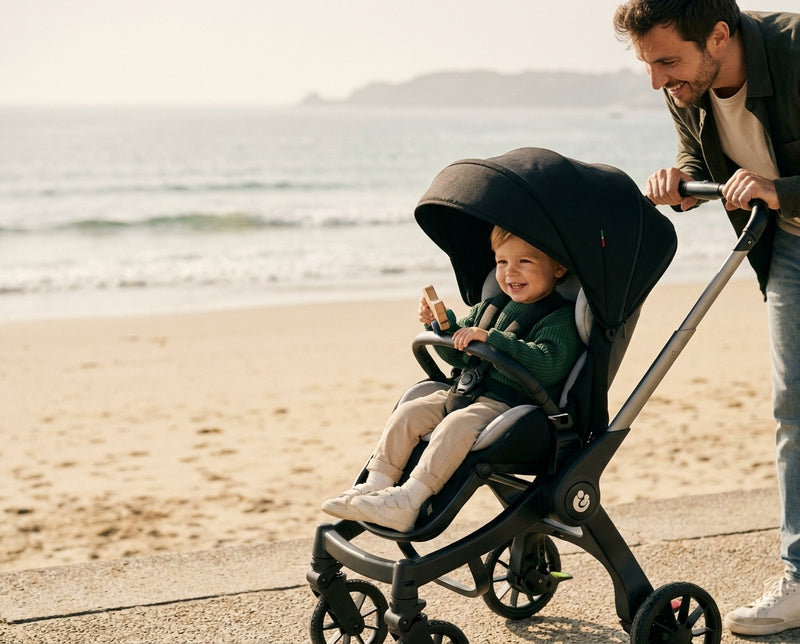 Enfant souriant dans la poussette 4 en 1 Grand Voyage en bord de mer